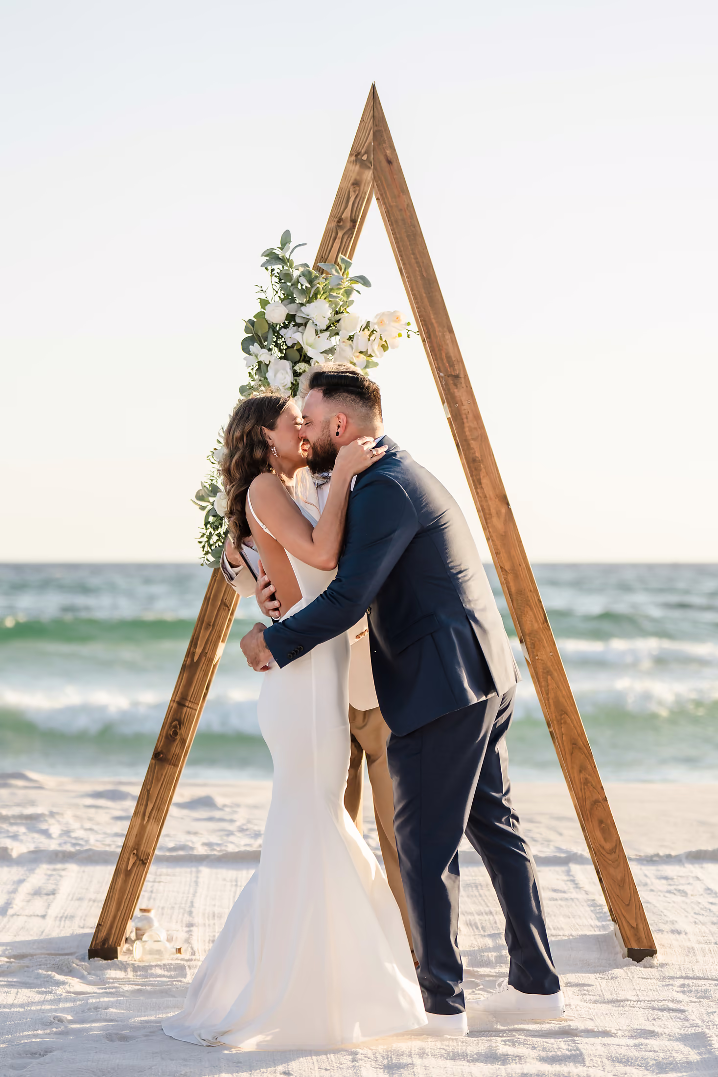 Couple kissing beneath a triangular arch on the beach